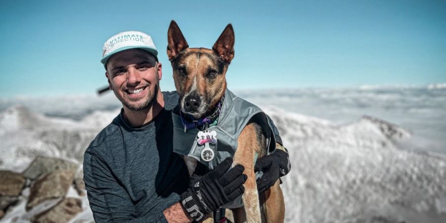 James Lauriello posing with his dog at the top of a peak in Colorado.