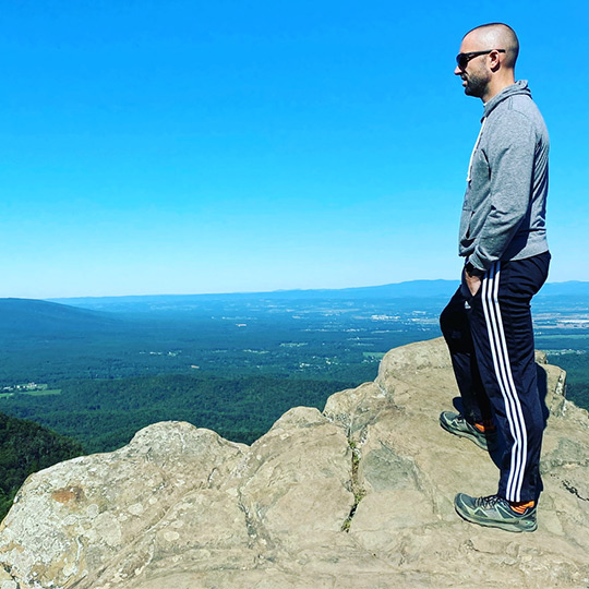 Joe Dean overlooking a cliff off a trail. 