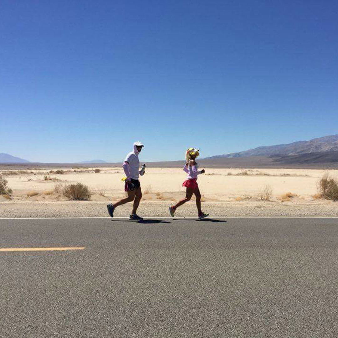 Two Team Injinji athletes running on an asphalt road at the Badwater 135 ultramarathon.