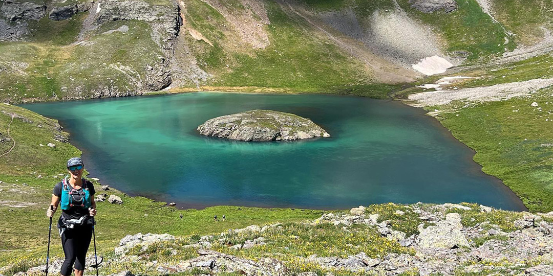 Team Injinji athlete Angela Shartel posing in front of an alpine lake at Hardrock 100 ultramarathon.