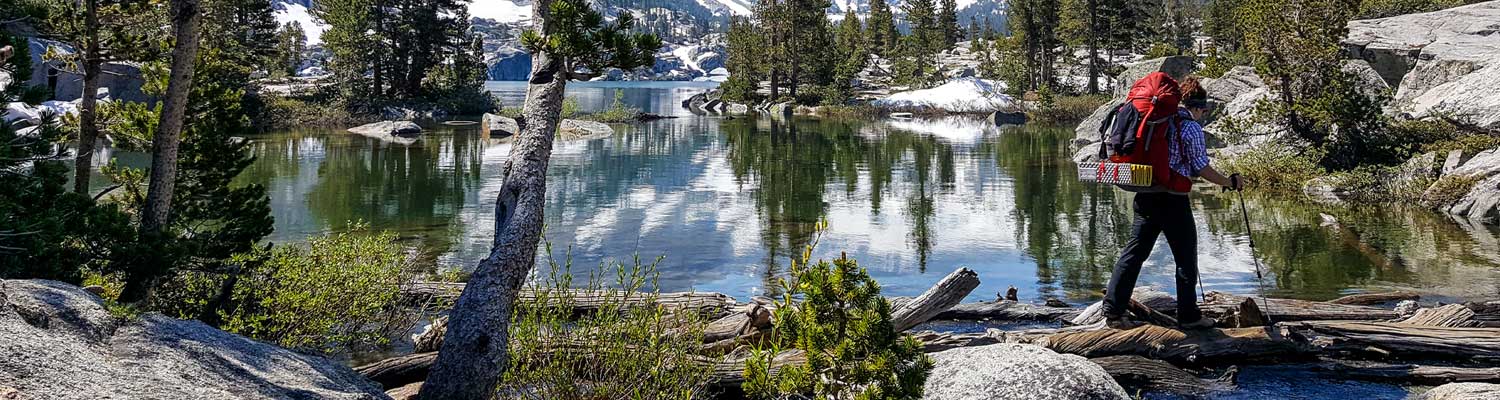 A backpacker hiking beside an alpine lake in the mountains. 