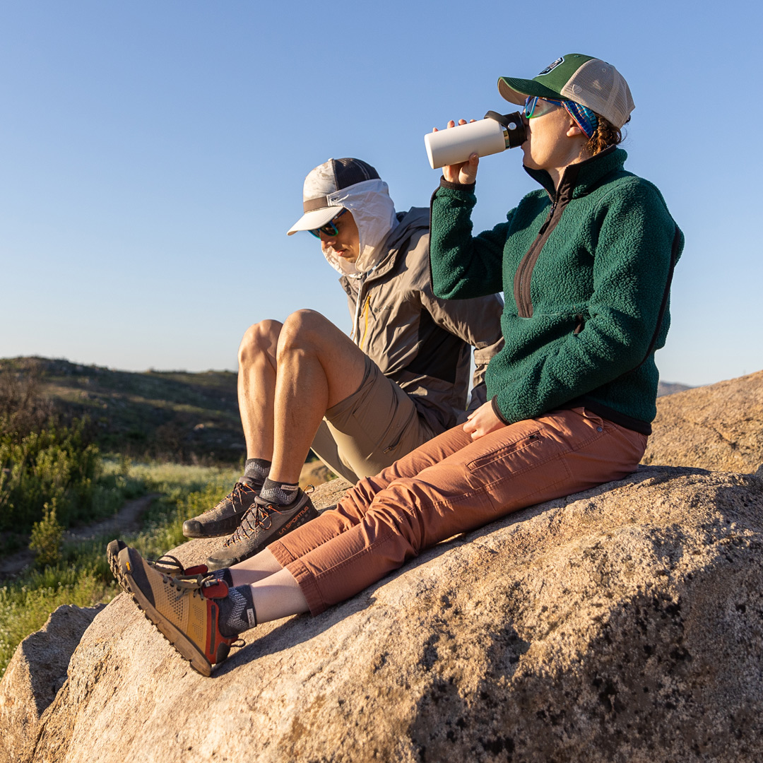 Two hikers relaxing on a boulder wearing the Outdoor Midweight Crew Wool and the Outdoor Midweight Mini-Crew Wool.