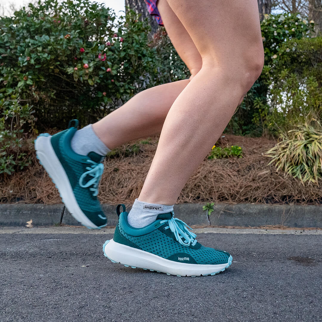 A man running on a wide sidewalk wearing the Injinji Run Lightweight Mini-Crew running socks in Navy. 